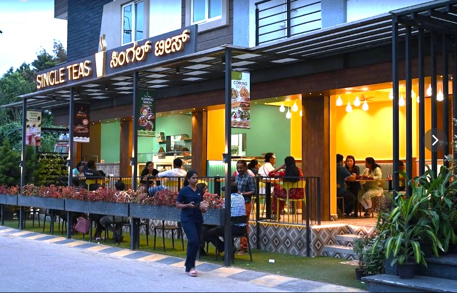 Single Teas cafe at ground floor with outdoor seating, warm lighting and customers dining